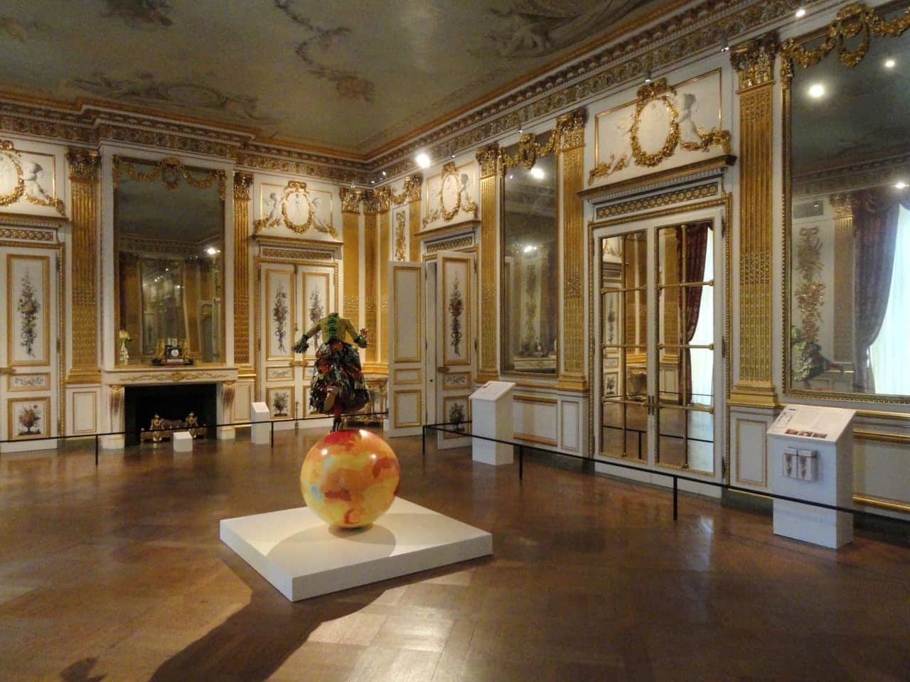 A gallery interior with gilded walls and a sculpture on display